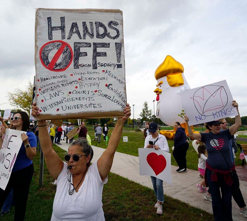 Francine Lombardo of Arlington Heights holds up her sign so drivers on Route 14 can see during the “No Kings” rally Saturday at Recreation Park in Arlington Heights.