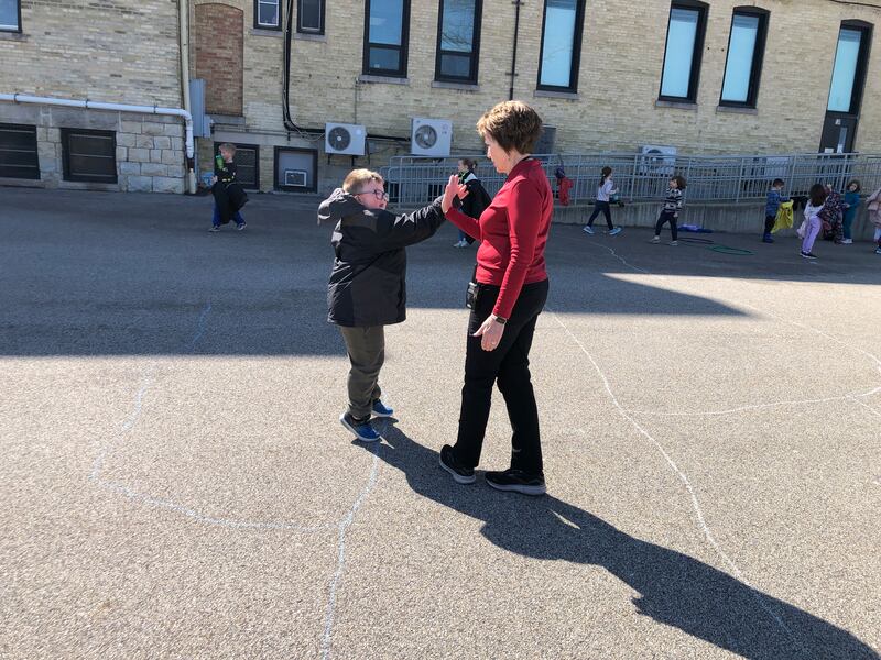 Principal Margaret Carey high-fives a student during a recent recess at McHenry's Landmark School. The school will close at the end of the current school year, and Carey will retire.