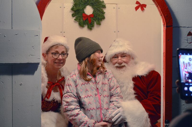 Elizabeth Pearce, 10, of Polo, smiles at Santa Claus as she poses for a photo with him and Mrs. Claus on Saturday, Dec. 2, 2023. Santa and Mrs. Claus visited Paul's Park in Polo to hear kids wish lists as part of the fifth annual Polo Christmas Festival.