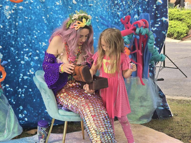 Mermaid Emily Easterly of Chicago encourages Alice Priz-Shoenberger, 5, of Chicago, to chose a prize from her treasure chest on Saturday, Sept. 20, 2025, at Joliet PrideFest, which was held at the Billie Limacher Bicentennial Park and Theatre in Joliet.