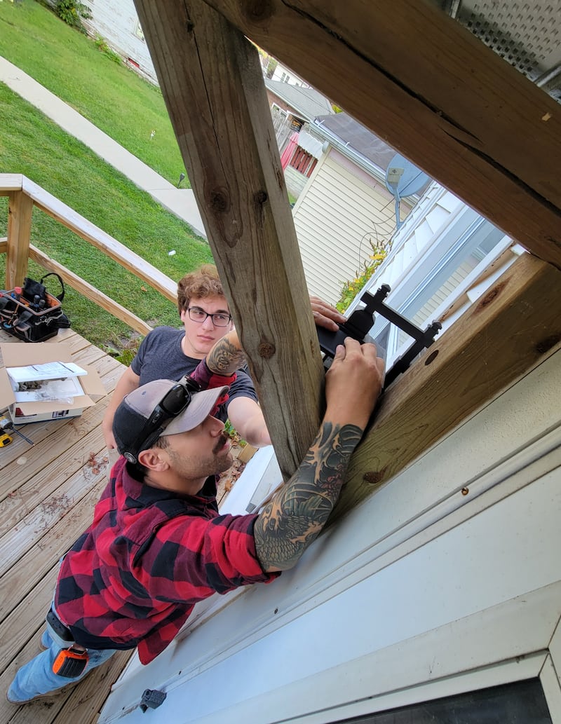 Zeben Parochetti (top) and Brandon DeJong replace a light fixture on a south side Ottawa home during Saturday's Labor of Love work day.