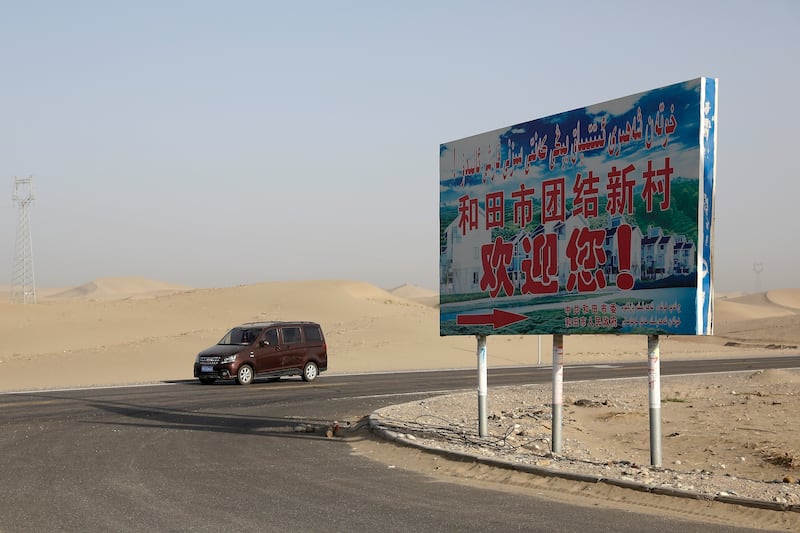 FILE - A car drives through a desert where a signboard which reads "Welcome to the Hotan Unity New Village" is seen on display in Hotan, in western China's Xinjiang region on Sept. 21, 2018. (AP Photo/Andy Wong, File)