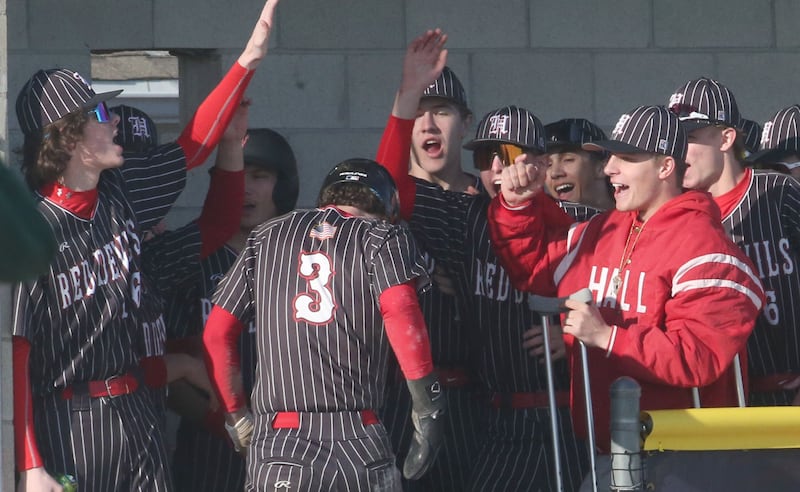Members of the Hall baseball team react as teammate Carson Riva steps into the dugout after scoring against St. Bede on Monday, March 31, 2025 at Schweickert Stadium in Peru.