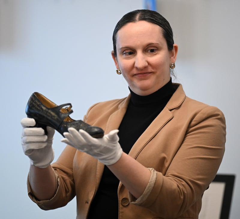 Karly Vance of the Elmhurst Art Museum shows artwork that is essentially a show with gold writing on it at the Roosevelt at Salt Creek Senior Living Community in Elmhurst on Wednesday, Feb. 11, 2026. The Mobile Museum is a program that brings original works of contemporary art from the Museum’s permanent collection directly to partner sites. Museum educators will transport three to five original artworks and lead a seminar-style experience that includes close-up viewing, guided discussion, and a hands-on art-making activity inspired by the works on view.