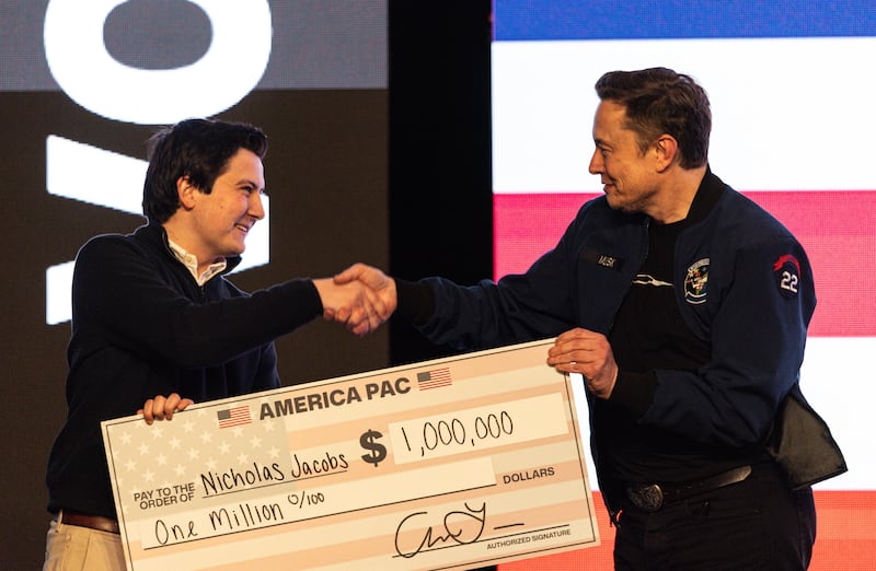 FILE - Elon Musk hands over a million dollar check to Nicholas Jacobs during a town hall in Green Bay, Wis., March 30, 2025. (AP Photo/Jeffrey Phelps, File)