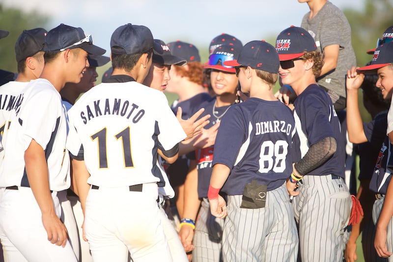 Team Japan and Team Fresno communicate with translator app on cell phone at the MCYSA 2022 Summer International Baseball Tournament hosted by McHenry County Youth Sports Association ate Lippold Park on July 21,2022 in Crystal Lake.