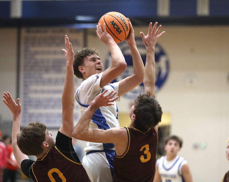 Woodstock's Max Beard (center) shoots the ball between Richmond-Burton's Gavin Radmer (left) and Dane Gardner (right) during a Kishwaukee River Conference boys basketball game on Wednesday, February. 4, 2026, at Woodstock High School.