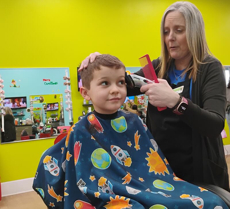 Oscar White, 7, sits for a haircut from stylist Chris Dobberstein at Pigtails & CrewCuts: Haircuts for Kids, 1318 Commons Drive, Geneva, on Saturday, Nov. 6, 2025. The salon franchise specializes in haircuts for children with autism or who have sensory sensitivities.