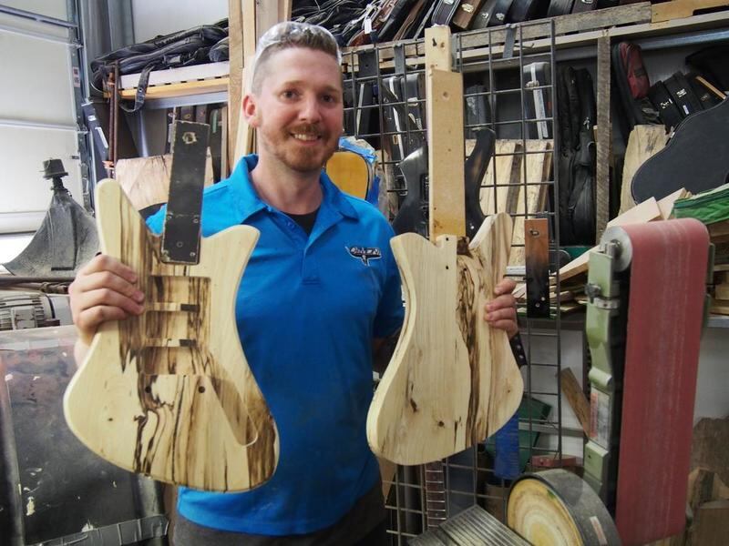 Nate Demont, owner of DeMont Guitars in Oswego, shows off a pair of unfinished guitar bodies made from white cherry wood in the company's workshop.