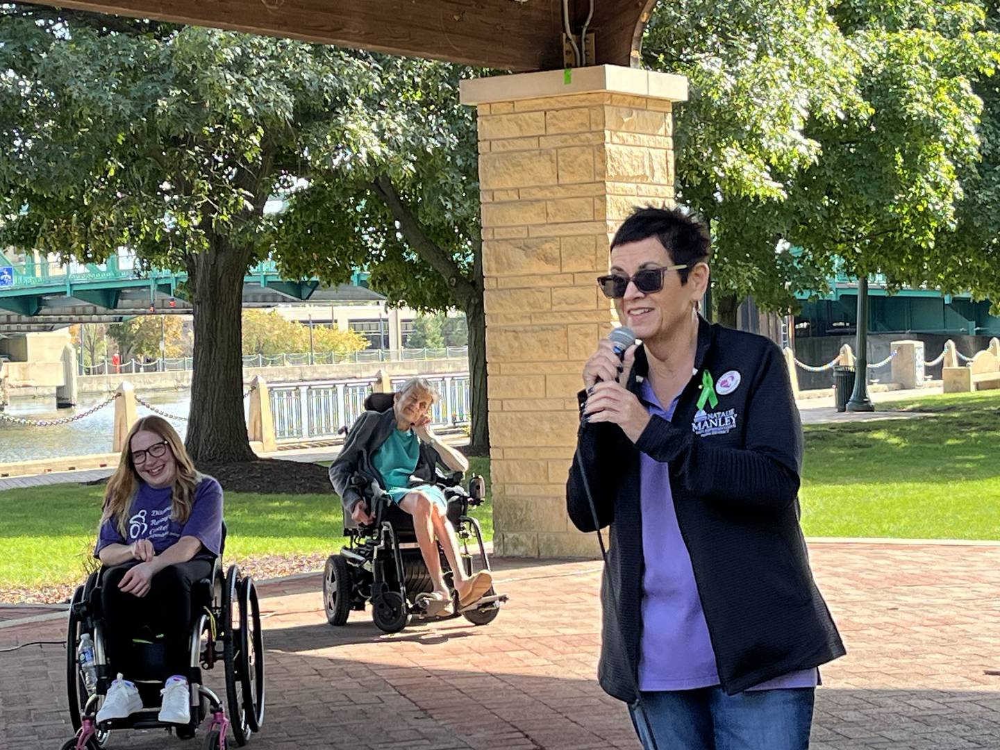 State Rep. Natalie Manley, D-Joliet, at Joliet's Disability Pride Fair on Saturday, Oct. 11, 2025. Manley delivers a speech while standing next to Riley Spreadbury (left), an independent living advocate for the Disability Resource Center in Joliet. Behind Spreadbury is Pam Heavens, a community access advocate for the United Cerebral Palsy Center for Disability Services in Joliet.