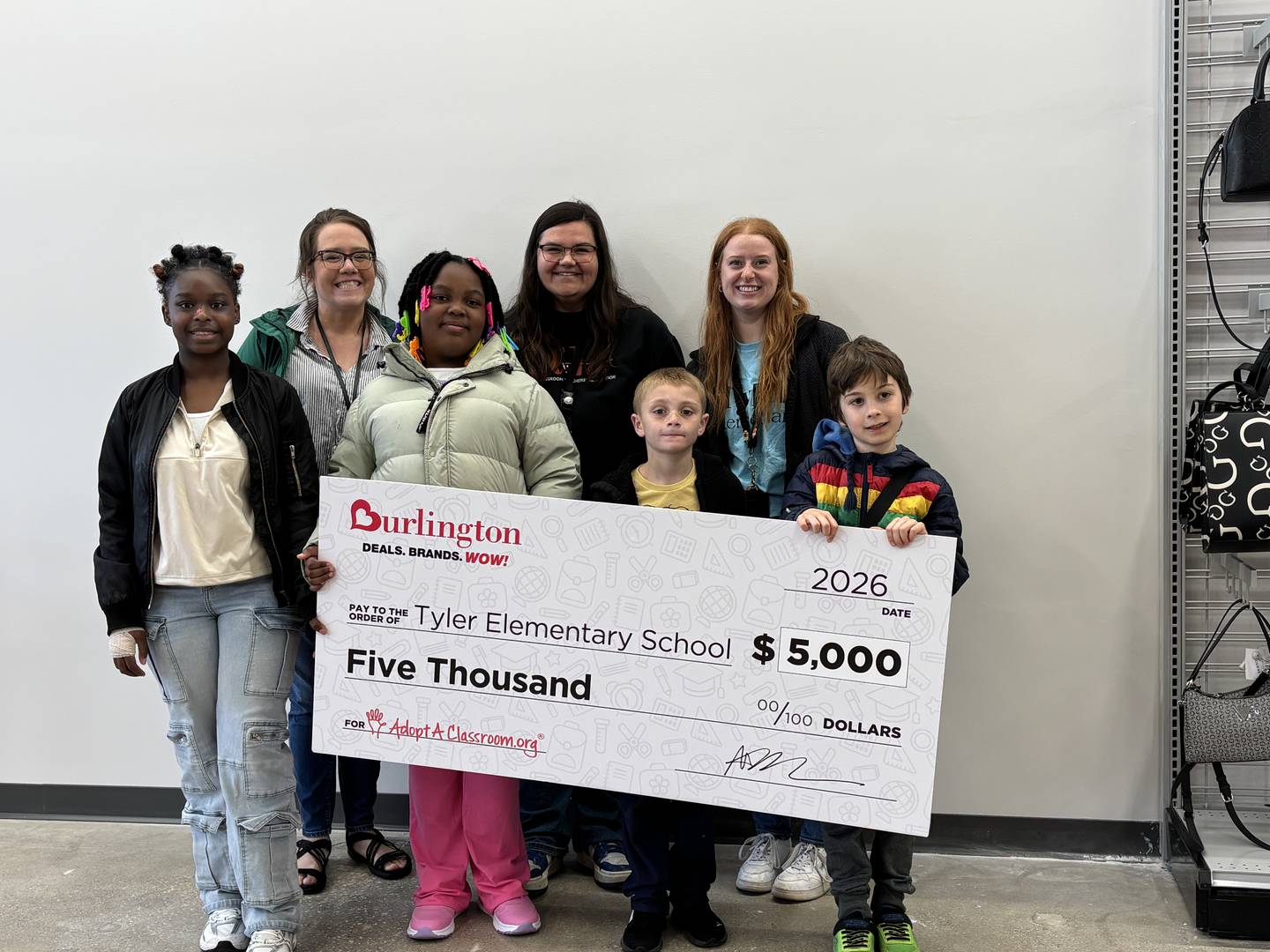 DeKalb second-grade teacher Kristina Swanson, math interventionist Alex Patinka and fourth-grade teacher Hannah Clark, along with Tyler Elementary School students, attended the grand opening event of the new Burlington store at 2250 Sycamore Road on Friday, May 1, 2026. The District 428 crowd was surprised with a $5,000 donation from Burlington Stores and AdoptAClassroom.org.