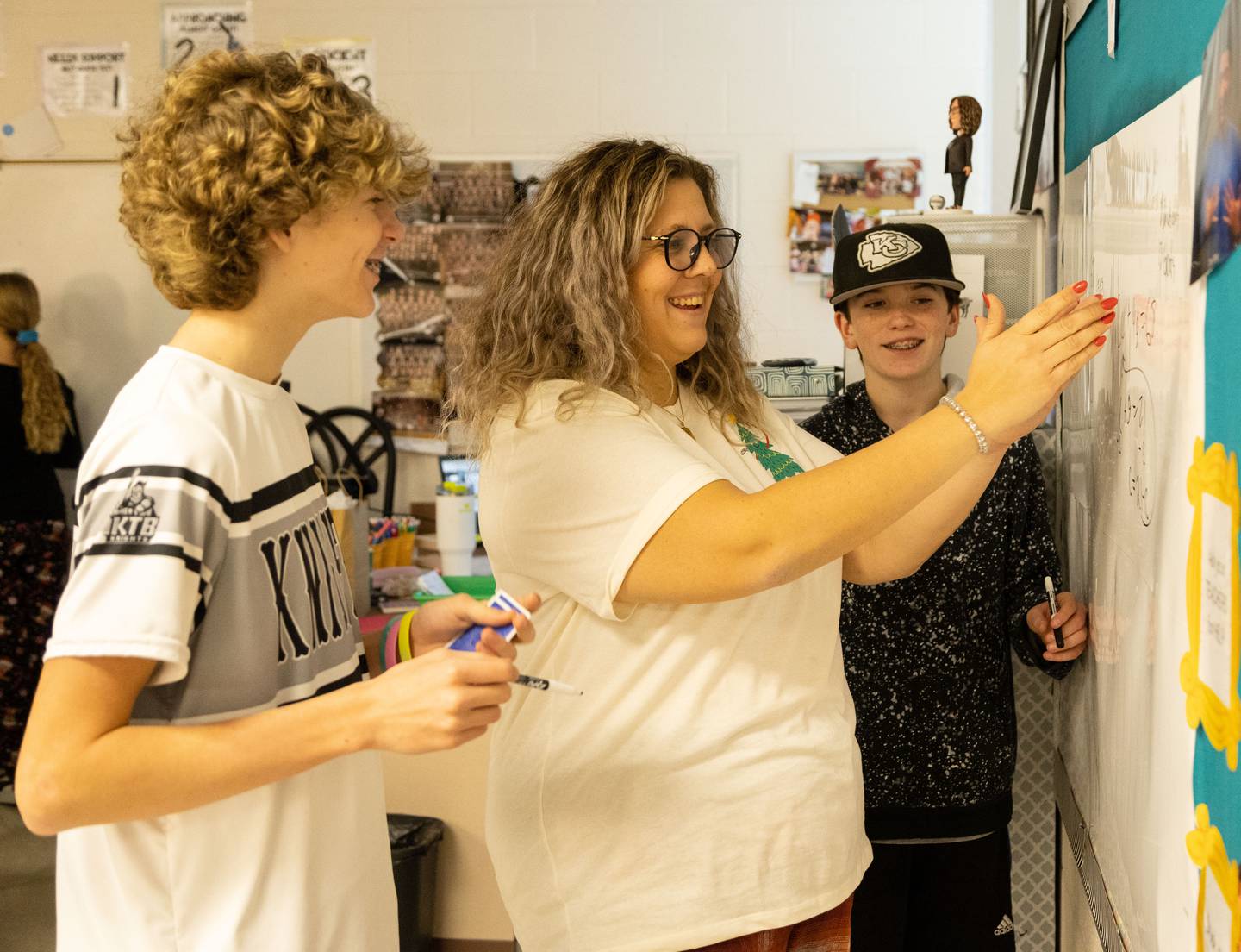 Alyssa Galvan, middle, gives Parker Balk (14),left, and Grant Caston (13) advice on how to solve a math problem during her 8th grade math class at Kaneland Harter Middle School in Sugar Grove on Monday Dec. 18, 2023.