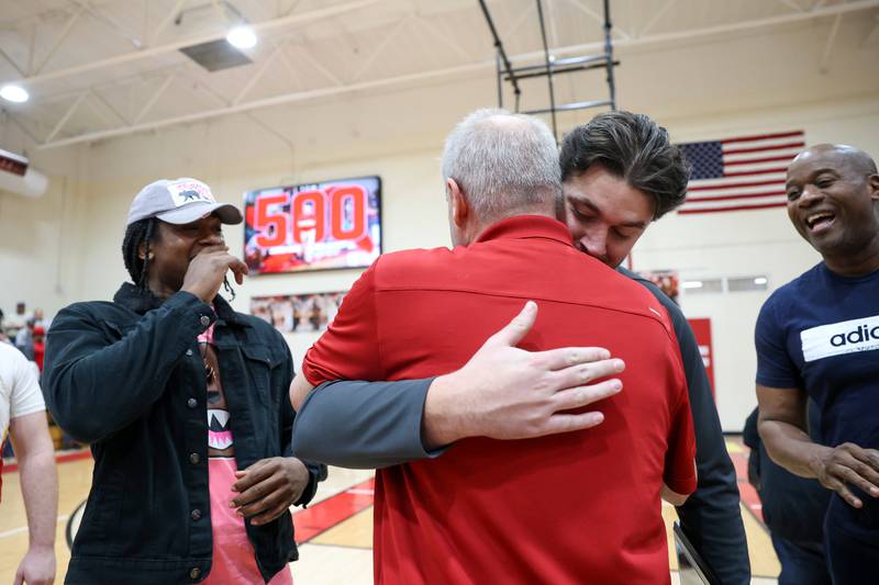 St. Anne head coach Rick Schoon hugs his son and assistant coach, Brooks Schoon, as he celebrates reaching his 500th career coaching win with a 64-43 victory over Momence in the River Valley Conference semifinals on Tuesday, Feb. 10, 2026.