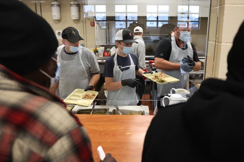 Marc Senffner, left, Tommy Cosgrove Jr. and his father Tom prepares meals for members of the community at the Daybreak Center on Thanksgiving Day in Joliet.