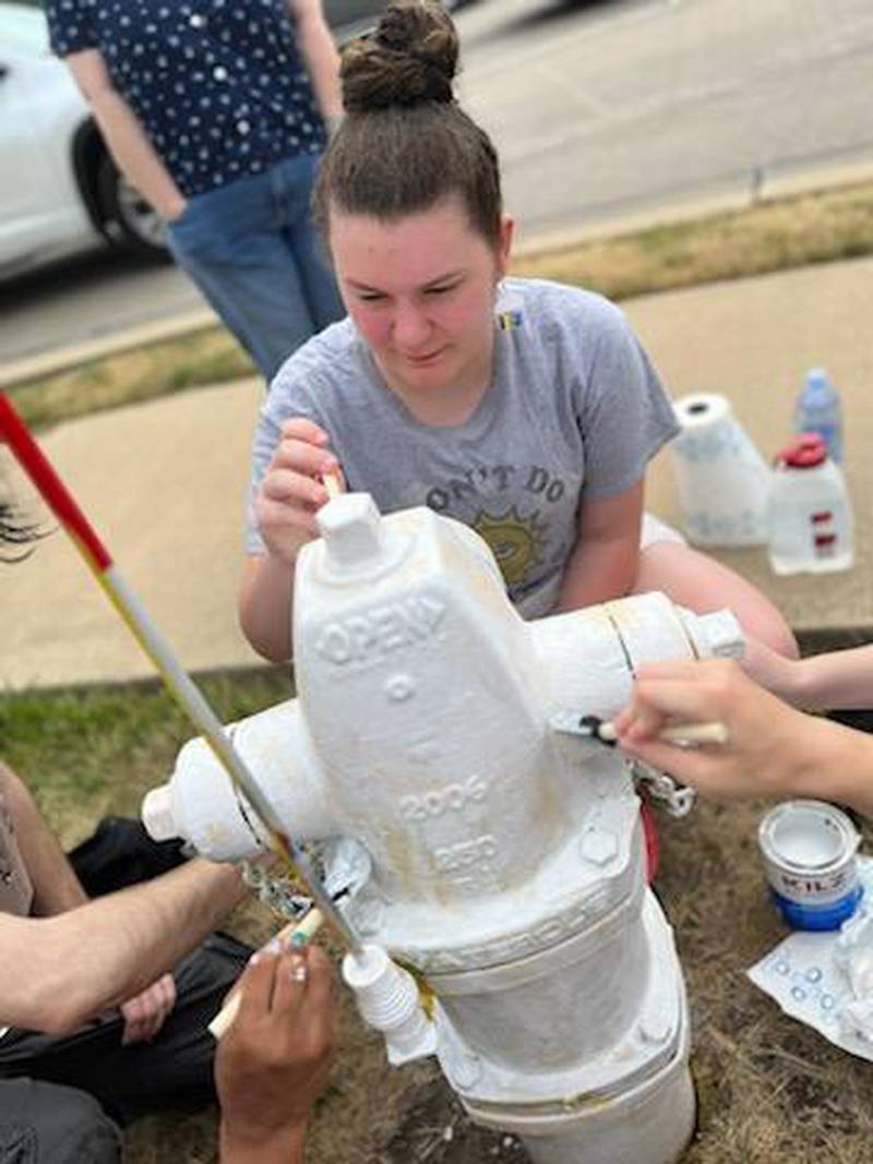 Lily McConnell with other volunteers repaint the vandalized rainbow pride-painted fire hydrant at the northwest corner of Kirk Road and East State Street in Geneva. The hydrant has been vandalized 12 times since July 2022. The hydrant was painted in pride colors as part of the city’s Art on Fire program.
