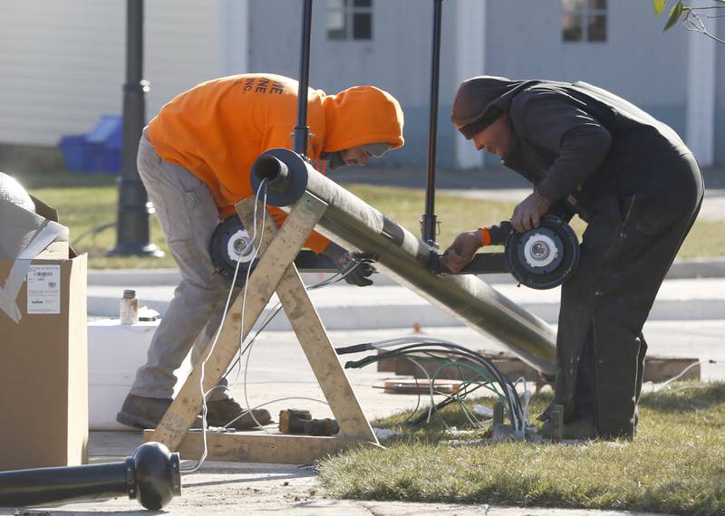 Workers put together a street light Tuesday Nov. 22, 2022, as they put the finishing touches on the Woodstock roundabout at intersection of Lake Avenue and South and Madison streets. Construction on the roundabout near Woodstock's downtown is expected to wrap up this week, opening traffic and marking the end of several months of construction. The roundabout has been in the works for several years and was built out this year.