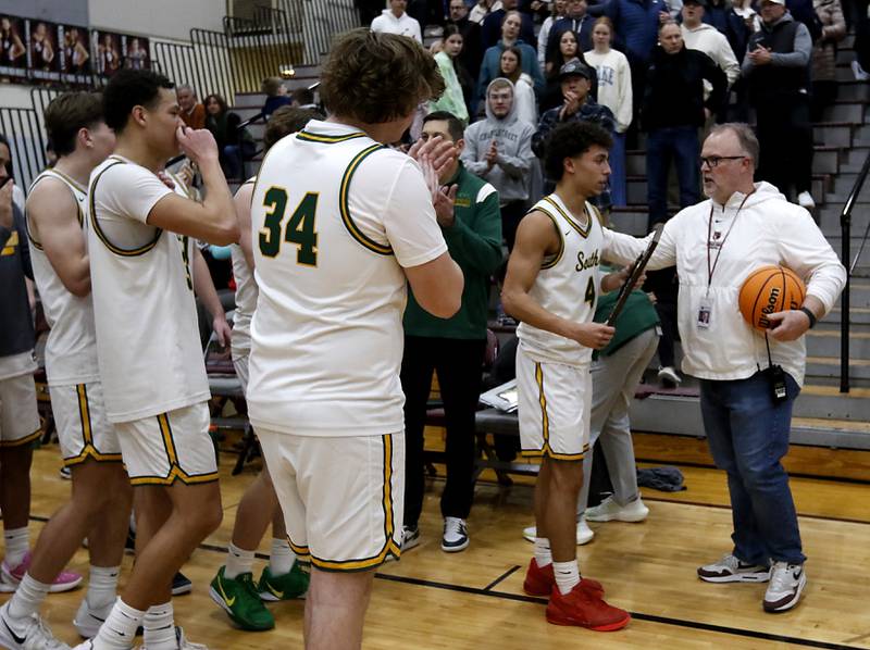 Prairie Ridge’s Chris Schremp hands Crystal Lake South's Anthony Demirov the trophy after Crystal Lake South defeated Cary-Grove in the IHSA Class 3A Prairie Ridge Regional championship basketball game on Friday, Feb. 28, 2025, at Prairie Ridge High School in Crystal Lake.