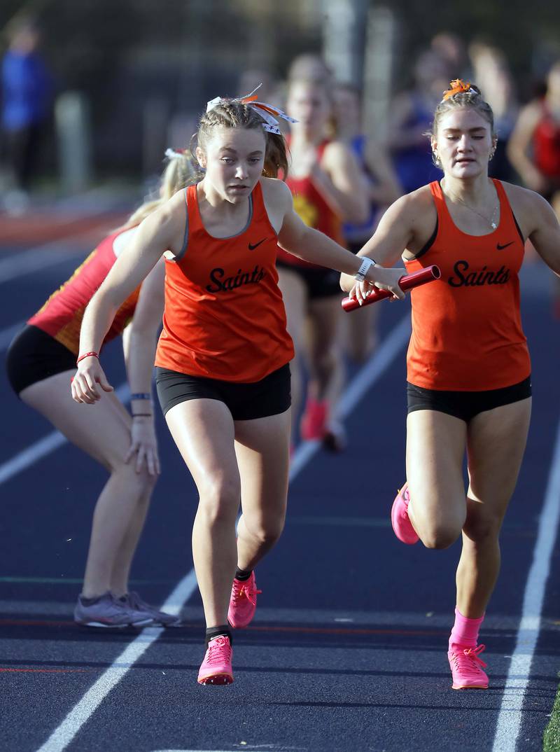 Lauren Lewison, of St. Charles East grabs the baton from Marley Andelman, right, in the Girls 4x800 Meter Relay during the Kane County girls track and field meet Thursday April 27, 2023 in Aurora.