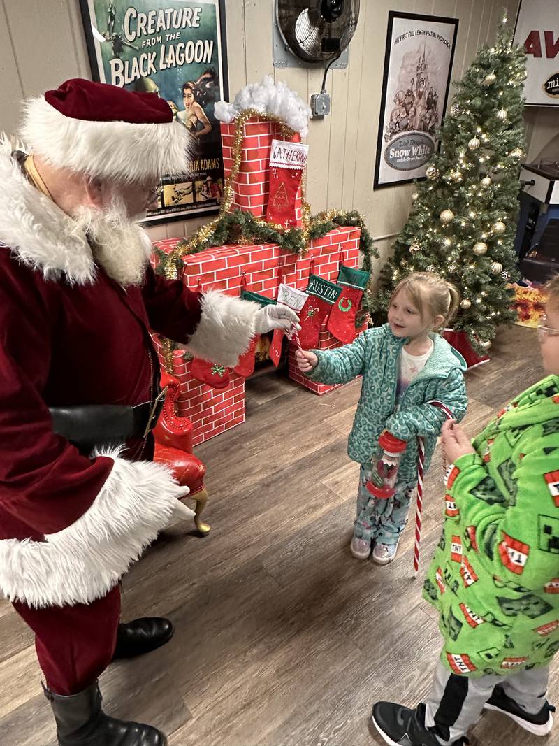 Danika Plancon of McHenry receives a candy cane from Santa as her brother, Donovan, looks on at the McHenry Outdoor Theater, where movies are scheduled until late December. A toy drive takes place Dec. 5-6, with a Santa sighting expected on Dec. 6.