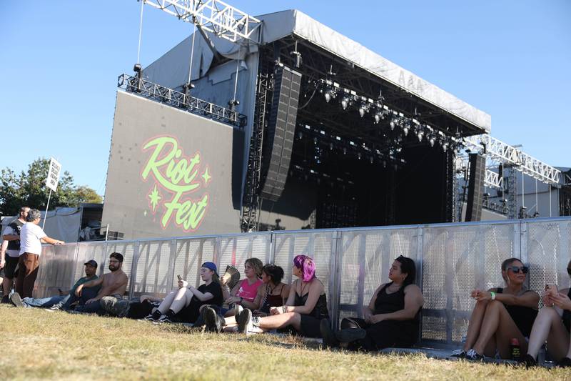 Festival goers find shade behind a fence between performances at Riot Fest on Friday, Sept. 20, 2024 in Chicago.