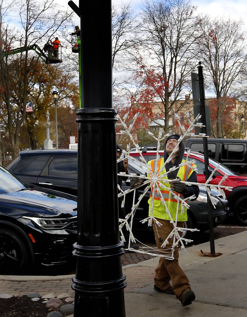 A city of Woodstock employee carries a  snowflake decoration while installing holiday decorations Tuesday, Nov. 12, 2024, around the historic Woodstock Square. Workers are preparing the Square for the city's annual Lighting of the Square event on Friday, Nov. 29.
