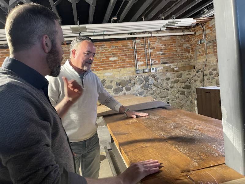 Woodstock Mayor Mike Turner (back) listens to Woodstock City Planner Darrell Moore explain when the new wooden bar for Mobcraft Brewery was installed in the Old Courthouse and Sheriff's House on Thursday, May 25, 2023.