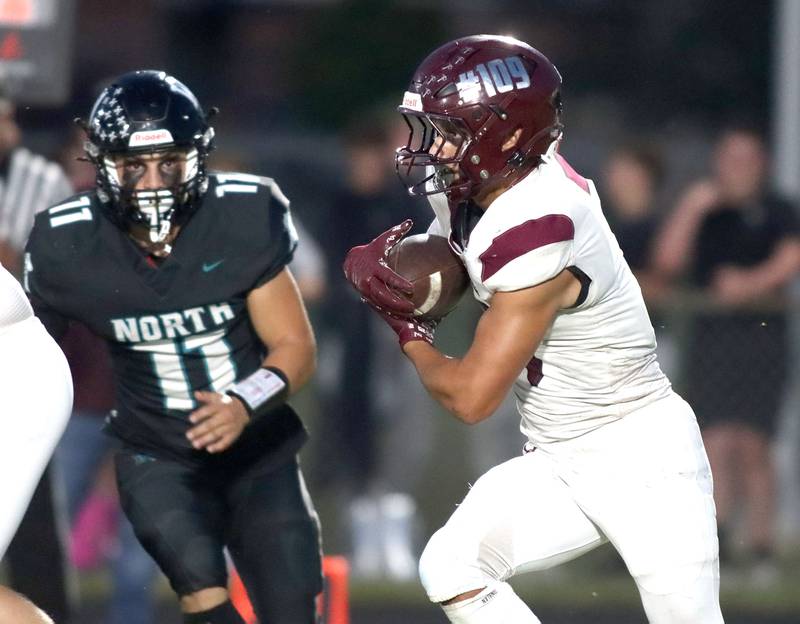 Marengo’s Gavin Baros runs the ball as Woodstock North’s George Kingos, left, closes in for a tackle in varsity football at Rod Poppe Field on the campus of Marengo High School in Marengo on Friday, Sept. 12, 2025.