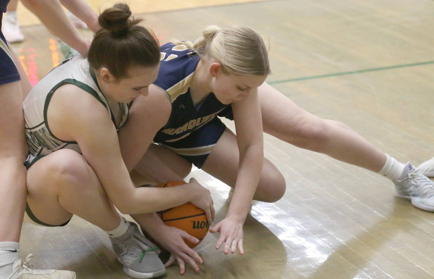 Midland's Ella Foster and Marquette's Chloe Thrush go after a loose ball under the hoop on Thursday, Feb. 12, 2026 at Midland High School.