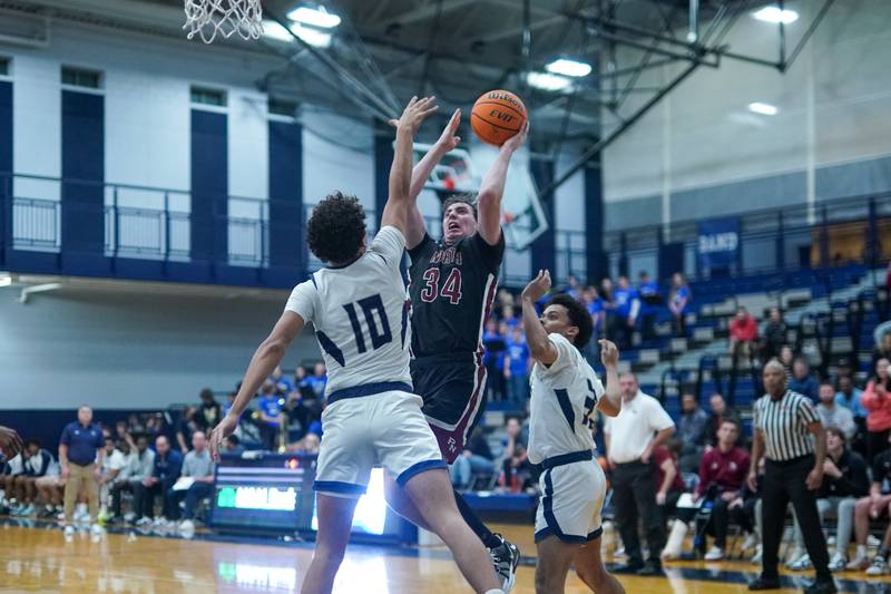 Plainfield North's Quintin Wiencek (34) shoots the ball in the post over Oswego East's Damien Lewandowski (10) during a basketball game at Oswego East High School on Friday, Dec. 6, 2024.