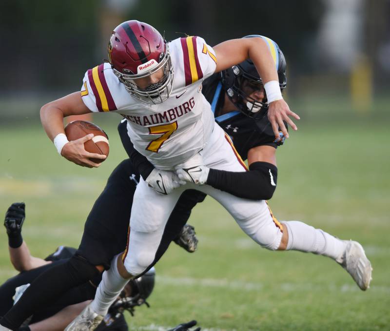 Joe Lewnard/jlewnard@dailyherald.com
Schaumburg quarterback Lucas Wagener gets tackled by Maine West’s Alexander Gorbenko during Friday’s game in Des Plaines.