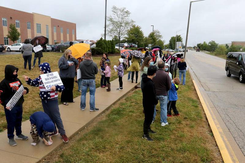 Demonstrators hold signs along Harnish Road on Tuesday during a rally for the reopening of in-person learning at the Algonquin-based Community School District 300 Central Office in Algonquin.