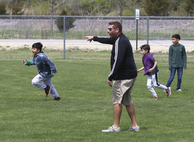 Jeremy Burke, a physical education teacher at Marengo Community Middle School, directs kids as they play capture the flag on Friday, April 28, 2023.