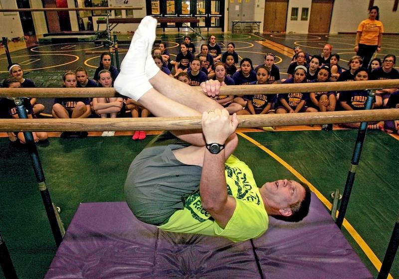 Fred Kaiser – or Phys Ed Fred – demonstrates a routine on the parallel bars bars during class Lundahl Middle School in Crystal Lake.