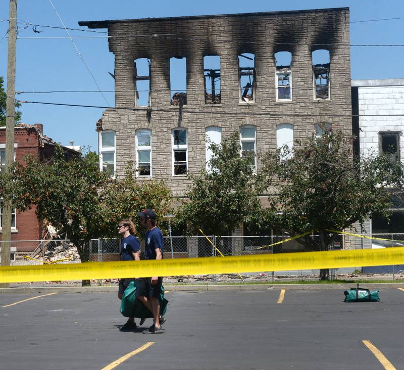 Two Sterling fire department workers carry a portion of a large Mutual Aid Box Alarm System (MABAS) tent Monday July 10, 2023. The tent was installed in the Wipfli parking lot across from the charred apartment building at 406 E. Third St., which was destroyed by a Friday fire.