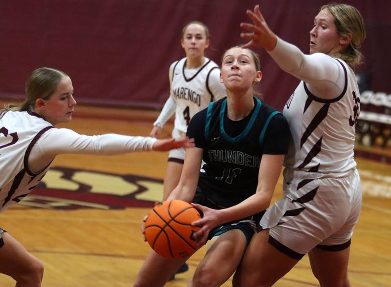Woodstock North’s Abigail Ward, center, moves with the ball as Marengo’s Macy Noe, right, defends in varsity girls basketball on Tuesday, Dec. 2, 2025, at Marengo High School in Marengo.