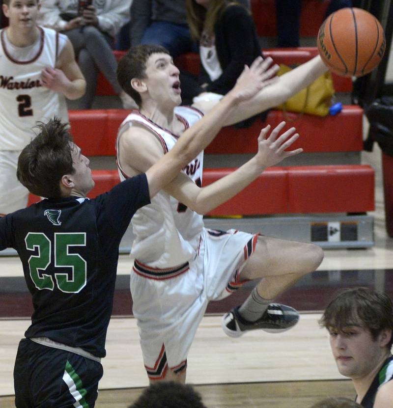 Woodland’s Jaron Follmer goes up and over Cornerstone Christian’s Elias Clinton for a layup attempt Monday, Feb. 19, 2024.