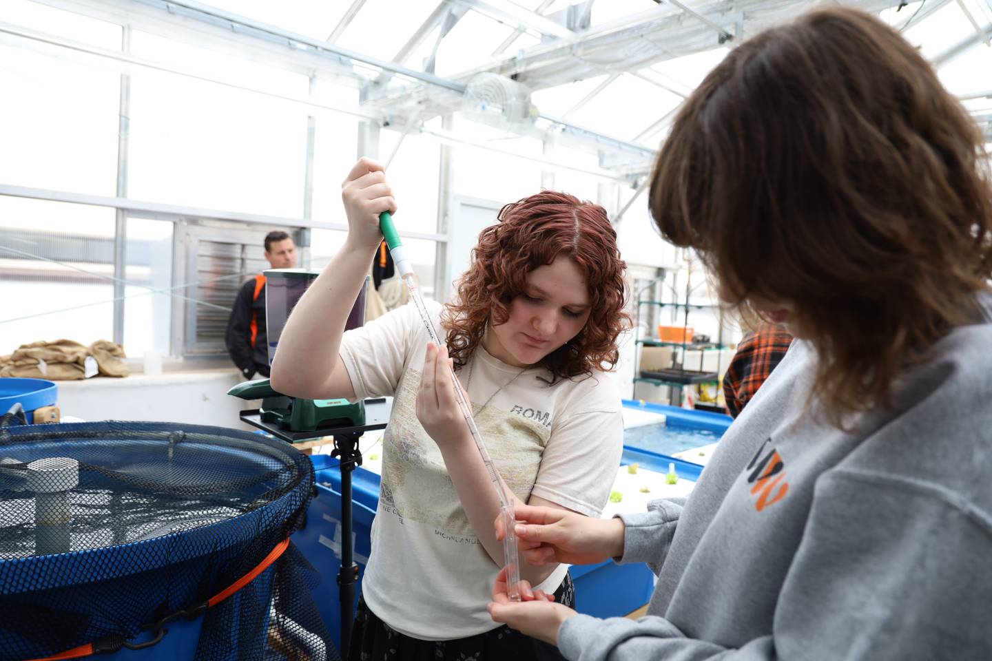 Megan Stephens and Alyssa Thomas, both 17-year-old juniors at McHenry High School’s Upper Campus, test water in the tilapia tank on March 22, 2023, as part of the school's aquaponics project.