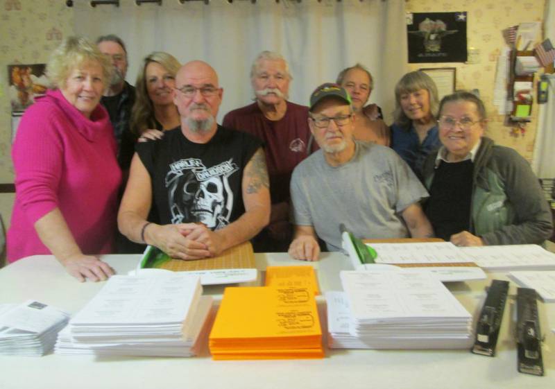 2024 Open Roads ABATE Summer Book committee members, including Patti and Kevin Smith, Sharyl and Sam Mataya, Cliff Oleson, Bill Kolb, Frank Lorang, Linda Oleson, and Sally Kolb are pictured with individual pages of the book ready to be cut, organized and stapled into over 400 books.