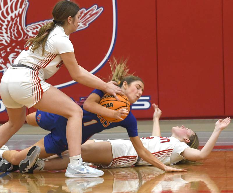 Genoa-Kingston's Presely Meyer hangs on to the ball as she hits the floor with Oregon's Lola Schwarz (left) and Addison Rufer (right) on Friday, Jan. 30, 2026 at the Blackhawk Center.