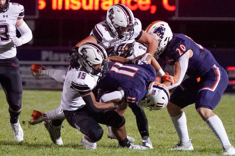 Plainfield North's Treycen Bownes (15) Colin Meyers (99) and Lucas Frydrychowski (21) tackle Oswego’s Theodore Manikas (11) during a football game at Oswego High School on Friday, Sept. 27, 2024.