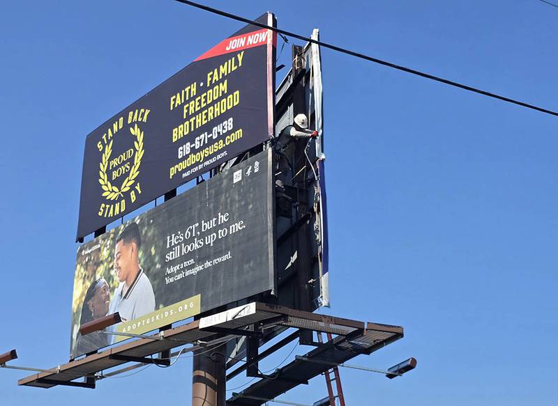 A Lamar Advertising representative on Monday moves an ad for the far-right extremist group Proud Boys; the sign was taken down entirely around noon Tuesday, Aug. 19, 2025.
