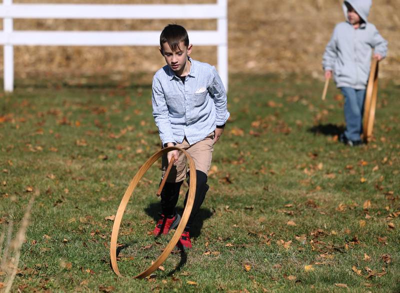 Southeast Elementary School third grader Liam Wolfe plays with a hoop and stick Tuesday, Nov. 4, 2025, as they learn about school in the 19th century during a visit to North Grove School, a one-room schoolhouse from 1878 in Sycamore.