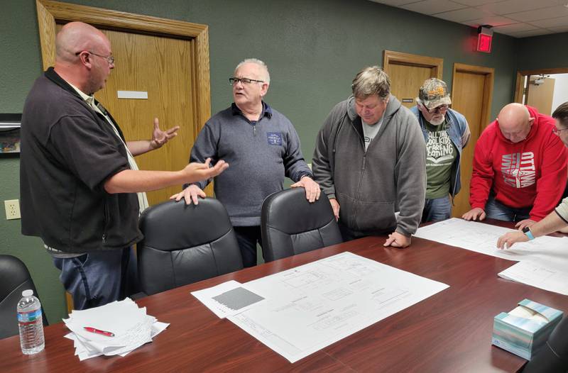 Marseilles Commissioner Mike Scheib (from left) and Mayor Jim Hollenbeck on Wednesday discuss the preliminary floor plans for the new city hall while members of the meeting's gallery check out the designs.