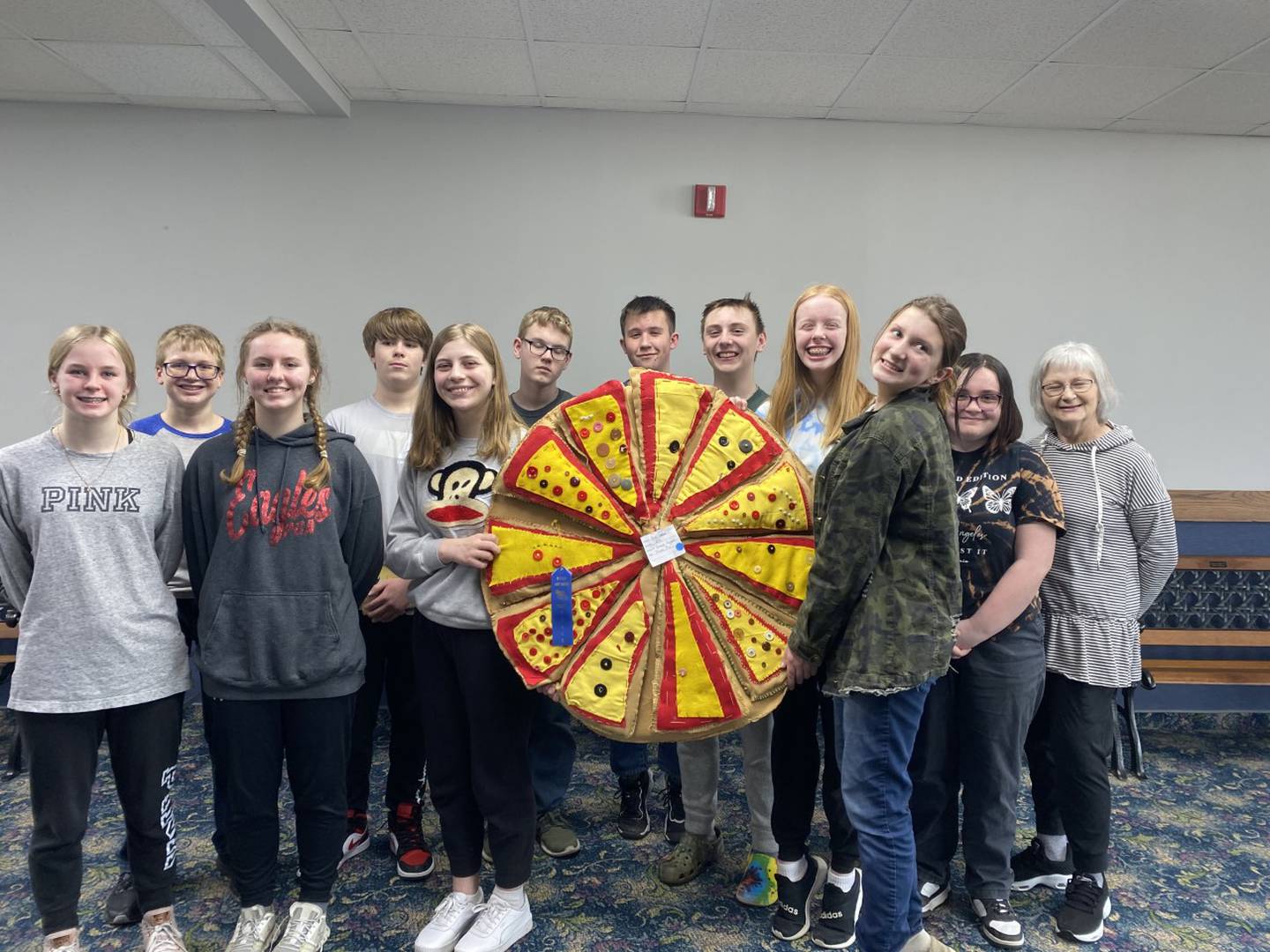 The Princeton Christian Academy eighth grade class took first place at the Bureau Valley Elementary Conference art contest at DePue for their hand sewn pizza, with each student creating his own piece from material and buttons and trims. Pictured are ( from left to right) Abby Harris, Trustin Crew, Isla Bayer, Steven Sharkey, Elyse Anderson, Connor Quaka, Michael Glass, Kellen Wall, Amelia Baker, Leah House, Presleigh Morrissey, and PCA art instructor Lane House.