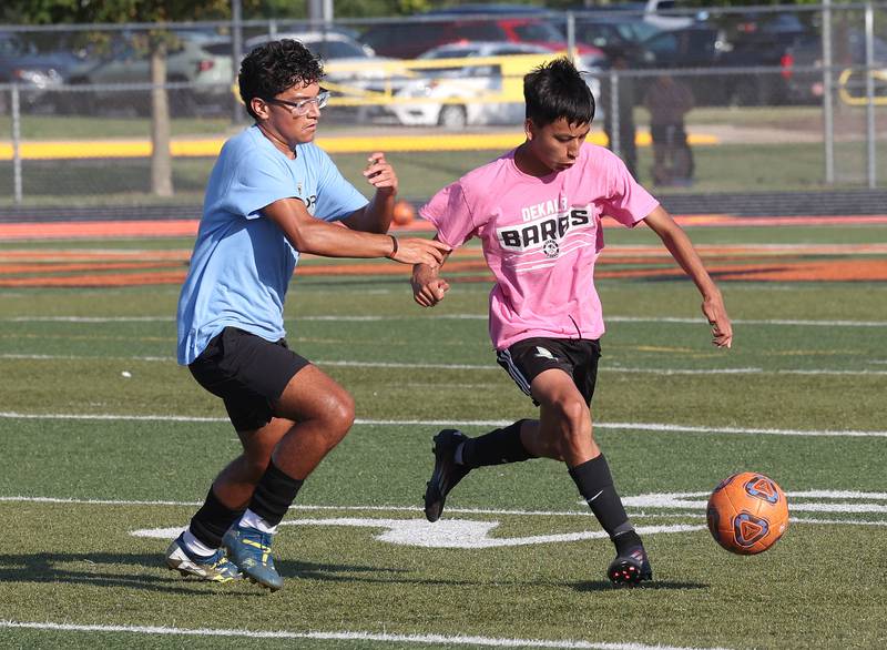 A DeKalb player pushes the ball by a Sycamore player Monday, July 14, 2025, during a summer boys soccer friendly at DeKalb High School.