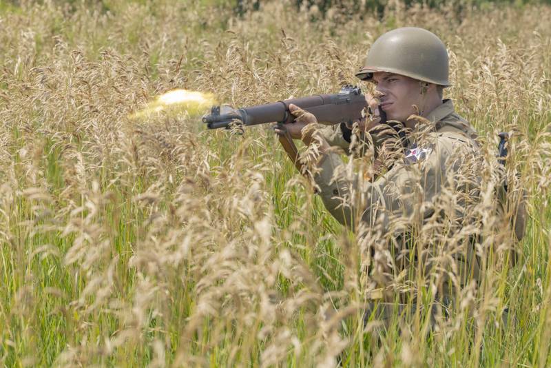 A flame from a muzzle blast leaves the gun of American reenactor Carson Graves while in a battle Sunday, July 14, 2024, during the Ottawa Military Show in rural Ottawa. All firearms used blanks to simulate the sights and sounds of an authentic battle during World War II.