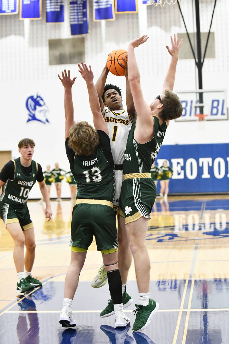 Joliet Catholic Academy's Jayden Armstrong looks to shoot under pressure from Bishop McNamara's Trey Provost (13) and Callaghan O'Connor during the Hilltoppers' 79-67 loss to the Fightin' Irish in the IHSA Class 2A Peotone Sectional semifinal on March 4, 2025.