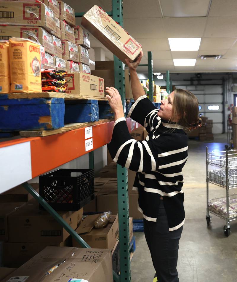Rooted for Good Executive Director Heather Edwards stocks shelves Thursday, Oct. 30, 2025, at the facility in DeKalb. The food pantry is preparing for the potential impact of SNAP benefits being cut off due to the government shut down and the large influx of new patrons it may bring.