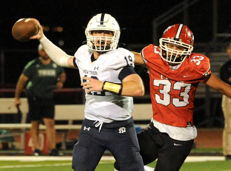New Trier quarterback Patrick Heneghan (19) pass under pressure from Yorkville pass rusher Jacob Homerding (33) during a varsity football game at Yorkville High School on Friday, Sep. 1, 2023.