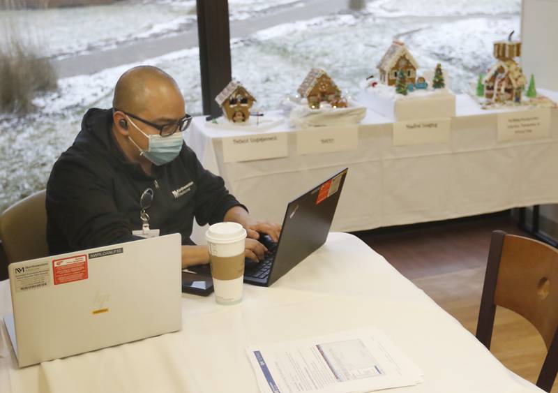 Jose Balloon works nears some of the over 30 gingerbread house made by different departments at Northwestern Medicine McHenry Hospital on display in the hospital’s cafeteria on Thursday, Dec. 22, 2022.